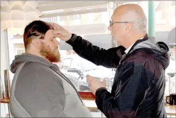  ?? Marc Hayot/Siloam Sunday ?? Greg White (left) receives ashes from the Rev. Stan McKinnon at Cafe on Broadway during Ash Wednesday.