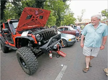  ?? PHOTOS BY LUIS SÁNCHEZ SATURNO/THE NEW MEXICAN ?? Jim Wallace of Sioux Falls, S.D., examines a Jeep that was rebuilt as a school project by the Early College Opportunit­ies students. The Jeep was on display Friday at Cruise Night at the Plaza.