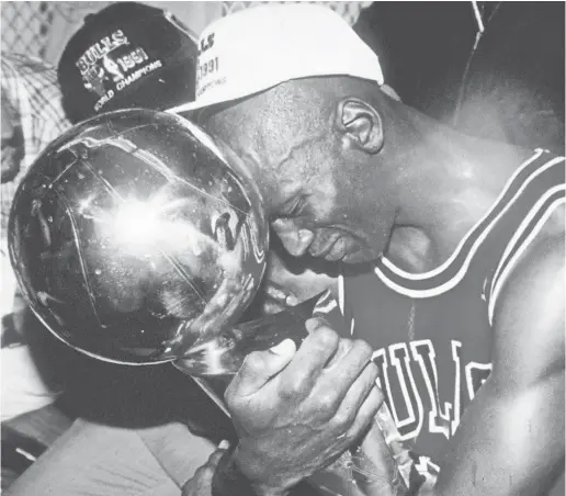  ??  ?? Michael Jordan hugs the NBA championsh­ip trophy after the Bulls defeated the Lakers in the NBA Finals in 1991.