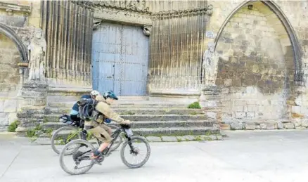  ?? ?? Dos peregrinos pasan con su bicis por la portada del edificio del Santo Sepulcro de Estella-lizarra.