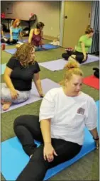  ??  ?? Diamond Credit Union of Pottstown employees look over their shoulders as they stretch during an after-work yoga class.