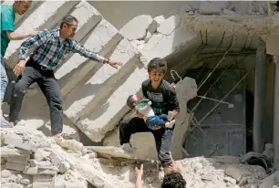  ??  ?? Syrians evacuate a toddler from a destroyed building following the air strike on Al Kalasa.