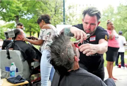  ?? STAFF PHOTOS BY ERIN O. SMITH ?? Curtis Wackler, a technician with The Blockhouse in Nashville, cuts Dave Sims’ hair Monday during Cuts for Change at Miller Park. Cuts for Change is an effort to help the homeless by providing haircuts and hygiene packs to those who can’t afford them.