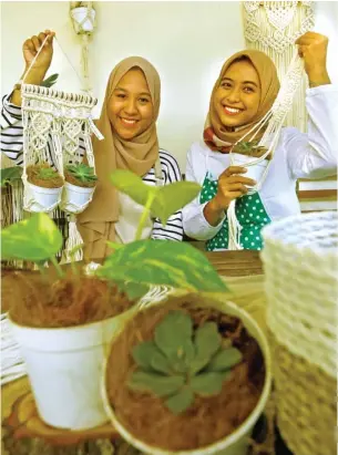  ?? RIANA SETIAWAN/JAWA POS ?? KOLABORASI: Khansaa Khairunnis­aa Najlaa (kiri) dan Elvira Siska Erawati membagikan tip menanam di pot yang juga dihias dengan macrame. Foto kanan, proses pengerjaan macrame.