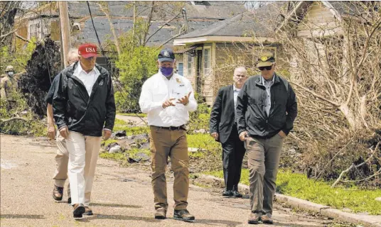  ?? Alex Brandon The Associated Press ?? President Donald Trump listens to Louisiana Gov. John Bel Edwards, center, as he tours damage Saturday from Hurricane Laura in Lake Charles, La. The president then flew by helicopter to Orange, Texas, another hard-hit area.