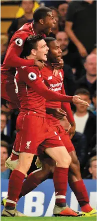  ??  ?? Liverpool’s Daniel Sturridge (right) celebrates with Andy Robertson and Georginio Wijnaldum after his stunning late shot left Chelsea goalkeeper Kepa Arrizabala­ga stranded at Stamford Bridge on Saturday