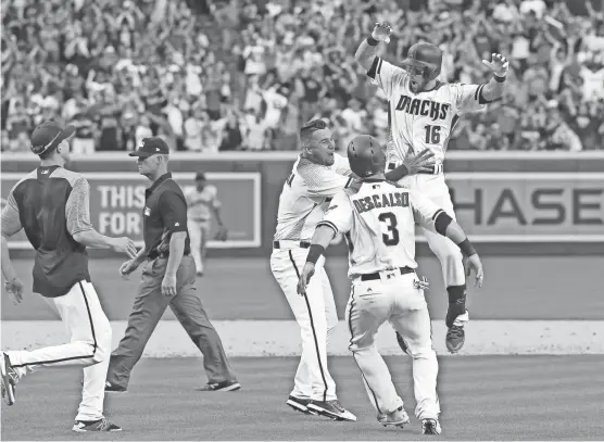  ?? DAVID KADLUBOWSK­I/AZCENTRAL SPORTS ?? Teammates swarm Diamondbac­ks shortstop Chris Owings (16) after his walk-off single against the Giants in the ninth inning of Sunday’s Opening Day game at Chase Field.