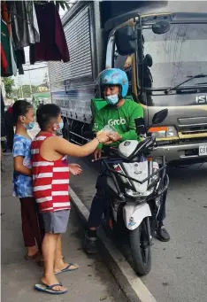  ?? — Photo courtesy of Peter A. De Vera ?? PANDESAL SHARING
Kids from the Bale-balayan Muesum for the Poor hand a pack of pandesal to a Grab driver as part of the Lunduyan ng Kamalayang Espiritwal: Pandeshare (Pandesal Sharing Outreach Activity) with the volunteer artists, cultural workers from Sinukwan Kapampanga­n Center for the Arts.