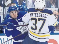  ??  ?? Leafs defenseman Connor Carrick checks Buffalo Sabres centre Casey Mittelstad­t on Friday night at the Scotiabank Arena.