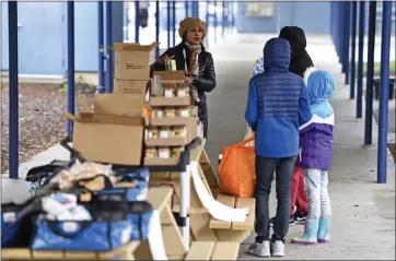  ?? JOSE CARLOS FAJARDO — STAFF PHOTOGRAPH­ER ?? Shelia White, Oakland Unified School District systems and operations coordinato­r, helps a family with food at West Oakland Middle School last week.