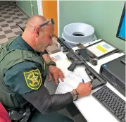  ?? BEN DICKMANN THE ASSOCIATED PRESS ?? A deputy at the Broward County sheriff’s office in Fort Lauderdale, Fla., processes paperwork to take possession of and destroy Ben Dickmann’s AR-style firearm. Dickmann decided to turn in his weapon after the shooting at Marjory Stoneman Douglas High School in nearby Parkland, Fla.