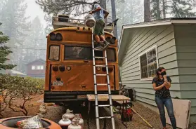  ?? Tracy Barbutes / Special to The Chronicle ?? Joseph Philipson and Ashley Bonetti load propane tanks on the roof of their school bus home as they evacuate during the Caldor Fire in South Lake Tahoe.