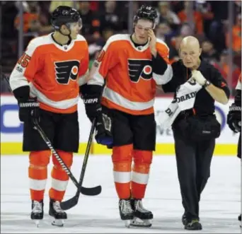  ?? TOM MIHALEK — THE ASSOCIATED PRESS ?? Flyers rookie Nolan Patrick, center, looks dazed after being helped off the ice by newcomer Flyer Jori Lehtera, left and Flyers medical services director Jim McCrossin early in the second period Tuesday night.