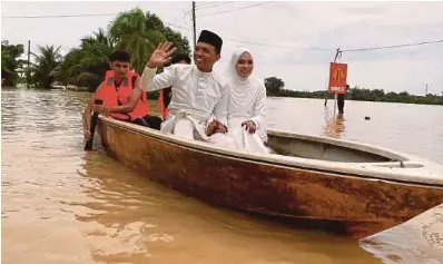  ?? ?? Pasangan pengantin baharu, Mohamed Khairie Mohamed Kamal dan Nur Izzatul Asma Mustafa menaiki bot meredah bah selepas inap desa disewa di Titi Besi, Kepala Batas dinaiki air.