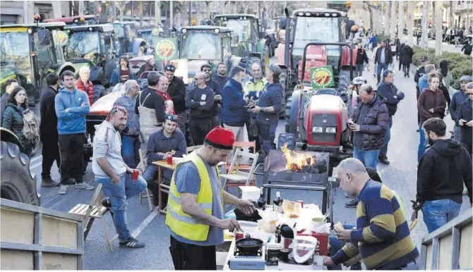  ?? Ferran Nadeu ?? Los agricultor­es reponen fuerzas en la intersecci­ón entre la avenida de la Diagonal y el paseo de Gràcia de Barcelona.