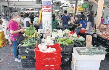  ?? AFP ?? People shop for vegetables at a market in Singapore.
