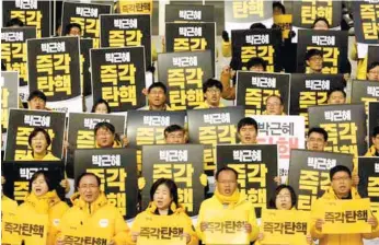  ?? (AP FOTO) ?? ‘IMPEACH PARK IMMEDIATEL­Y.’ Lawmakers and members of opposition Justice Party hold signs during a rally demanding the impeachmen­t of South Korean President Park Geun-hye at the National Assembly in Seoul, South Korea. Park, who faces the political...