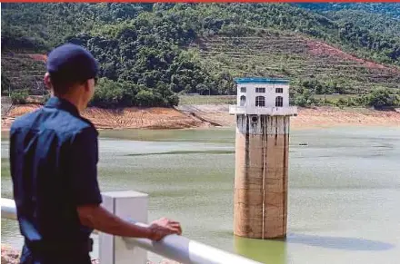  ?? BY DANIAL SAAD PIC ?? A guard observing a tower marked by receding water levels in Teluk Bahang dam in Penang yesterday.