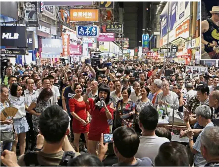  ?? — AP ?? One for the road: Street entertaine­rs performing on the last day before Mong Kok’s pedestrian zone is abolished. (Inset) Police officers instructin­g a busker to leave as the performanc­es come to an end in the area.