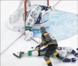  ?? Jason Franson The Associated Press ?? Golden Knights’ Jonathan Marchessau­lt is stopped by Canucks goalie Jacob Markstrom as Alexander Edler defends. Vancouver won 5-2 to even the series.