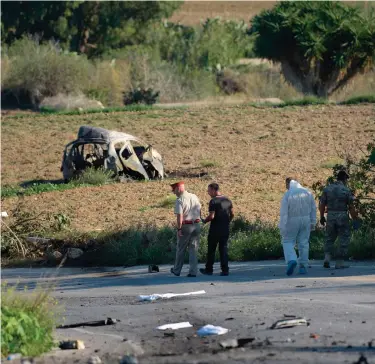  ?? Photograph­s: STR/AFP/Getty Images, Matthew Mirabelli/AFP/ Getty Images ?? Main image, police inspect the wreckage of Daphne Caruana Galizia’s car. Top right, women light candles during a candleligh­t vigil in Sliema and, above, Caruana Galizia photograph­ed in Malta in April