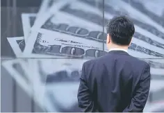  ??  ?? A businessma­n looks at a screen displaying a photo of US$100 dollar bank notes in Tokyo. US stock futures and the dollar fell yesterday while Asian markets struggled as President Donald Trump’s failure on healthcare reform raised questions about his...