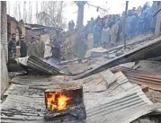  ?? (AFP) ?? People gather outside a damaged house after a gunfight between militants and forces on the outskirts of Srinagar on Sunday