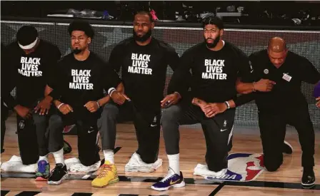  ?? Getty Images vía AP ?? LeBron James (en el centro) se arrodilló para escuchar el himno nacional junto al resto de los Lakers y los Clippers antes del partido de la NBA entre ambos equipos el jueves 30 de julio en Lake Buena Vista, Florida.