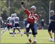  ?? THE ASSOCIATED PRESS ?? New England Patriots quarterbac­k Tom Brady (12) passes the ball as offensive coordinato­r Josh McDaniels, right, looks on during an NFL football training camp practice, Thursday, July 25, 2019, in Foxborough, Mass.