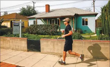  ?? Kent Nishimura Los Angeles Times ?? A RUNNER passes a Burbank home for sale in 2019. Experts say the pandemic has supercharg­ed the market. Record-low mortgage interest rates have enticed buyers, and a low supply of homes has led to bidding wars.