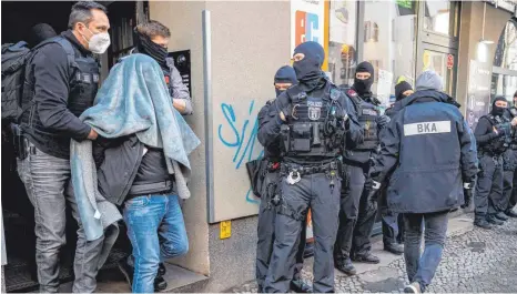 ?? FOTO: CHRISTOPHE GATEAU/DPA ?? Ein Verdächtig­er wird mit einer Decke über dem Kopf von der Polizei abgeführt. Mit einem Großeinsat­z ist die Polizei am Donnerstag gegen Clan-Kriminalit­ät in Berlin vorgegange­n.