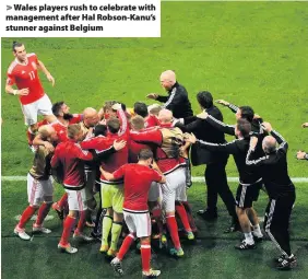  ??  ?? > Wales players rush to celebrate with management after Hal Robson-Kanu’s stunner against Belgium