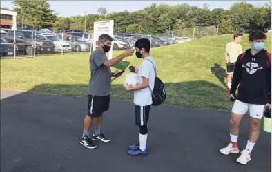  ?? Bill Bloxsom / Hearst Connecticu­t Media ?? Trumbull boys soccer coach Sil Vitiello checks a player’s temperatur­e prior to Monday's practice.