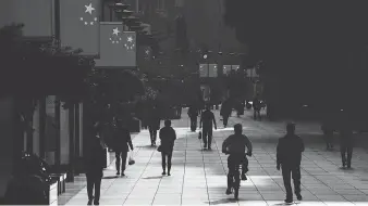  ?? JOHANNES EISELE/AFP/GETTY IMAGES ?? People walk along a shopping street in Shanghai. Allowing families to have as many children as they want could be a significan­t step toward buoying China’s economy, Joe Chidley writes.