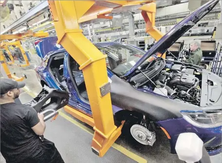  ?? Paul Sancya Associated Press ?? A WORKER BUILDS a 2015 Chrysler 200 automobile at the Sterling Heights Assembly Plant in Sterling Heights, Mich., in 2014.