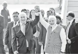  ?? — Gambar Reuters ?? TETAP MESRA: Netanyahu (kiri) dan Modi mengangkat tangan selepas perdana menteri Israel itu tiba di lapangan terbang New Delhi, India, kelmarin.