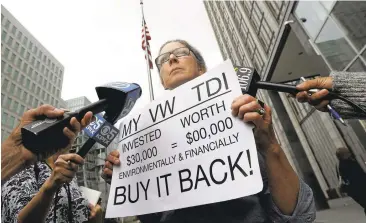  ?? JEFF CHIU/ASSOCIATED PRESS ?? Joyce Ertel Hulbert, owner of a 2015 Volkswagen Golf TDI, holds a sign while being interviewe­d Thursday outside of the Phillip Burton Federal Building in San Francisco. Car owners and the Department of Justice have sued the carmaker.