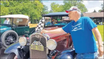  ?? CAROLE CARLSON/POST-TRIBUNE PHOTOS ?? Dan Dieck, of Hebron, places a checkered flag on his 1931 Model A roadster Saturday after completing the Cobe Cup Cruise, which ended at the Lake County Fairground­s in Crown Point.