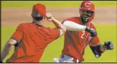  ?? Bryan Woolston The Associated Press ?? Reds right fielder Nick Castellano­s elbowbumps manager David Bell after slugging a two-run homer during Wednesday’s intrasquad game in Cincinnati.