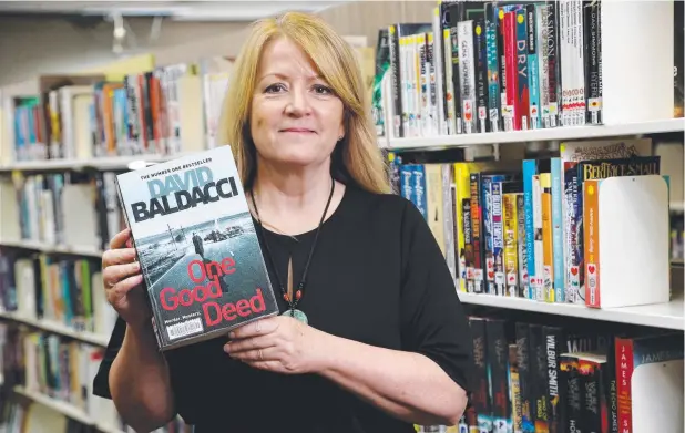  ?? Picture: STEWART McLEAN ?? PAGE-TURNER: Cairns City Library’s Karen Maguire with the most popular book for the past year,
One Good Deed by David Baldacci.
