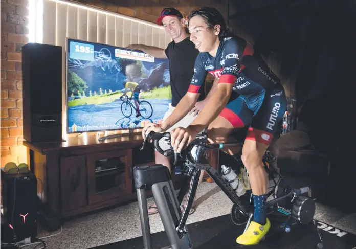  ?? Picture: Nev Madsen ?? ON TRACK: Darling Downs Cycling Club Trent West watches Declan Trezise tackle a steep climb on a cycling VR simulator. A donation from the club is allowing Trezise to purchase similar equipment to use for his training.