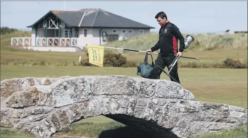  ?? PICTURE: ANDREW MILLIGAN/PA ?? Greenkeepe­r Simon Connah crosses the Swilcan Bridge on the Old Course at St Andrews, in Fife, as final preparatio­ns are completed to the course ahead of reopening today. Golfers were able to return in England earlier this month but lockdown protocals have been tighter in Scotland.