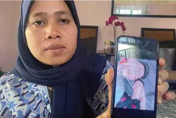  ?? ?? SITI Fairuz menunjukka­n gambar anak sulungnya, Muhammad Fahmi Adlan (berbaju hitam) yang ditemukan lemas di Sungai Mata Ayer, Pulai Chondong.