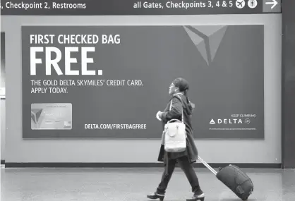  ?? Associated Press file photo ?? ABOVE: A traveler walks past a sign advertisin­g a Delta Air Lines credit card on March 24, 2015, at SeattleTac­oma Internatio­nal Airport in SeaTac, Wash. Airline loyalty programs are losing much of their allure even for frequent flyers, and the rules...