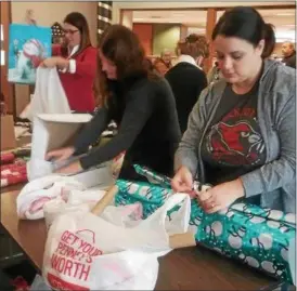  ?? JEAN BONCHAK — THE NEWS-HERALD ?? Volunteers keep busy wrapping donated Christmas gifts for Lake County seniors in need on Dec. 15 at Mentor Municipal Center.