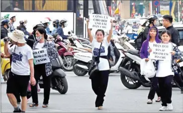  ?? AFP ?? Protesters display placards as they march towards a courthouse during the trial of a prominent lawyer and five other activists in Hanoi on Thursday.