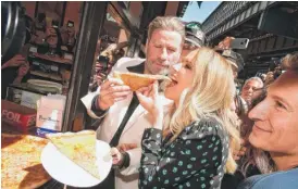  ?? THEOWARGO/ GETTY IMAGES ?? John Travolta and wife, Kelly Preston, enjoy slices of Lenny’s Pizza on Tuesday in Brooklyn, New York.