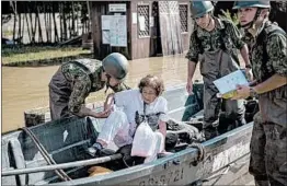  ?? CARL COURT/GETTY ?? Soldiers evacuate a woman following heavy flooding Sunday near Okayama, Japan.