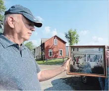  ?? DAVE JOHNSON THE WELLAND TRIBUNE ?? Gord Minor with a photo of his family home destroyed by fire.