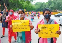  ?? — AFP ?? Asha hold placards and shout slogans during a protest to draw attention to their plight of underpayme­nt and lack of protection from Covid in New Delhi on Sunday.